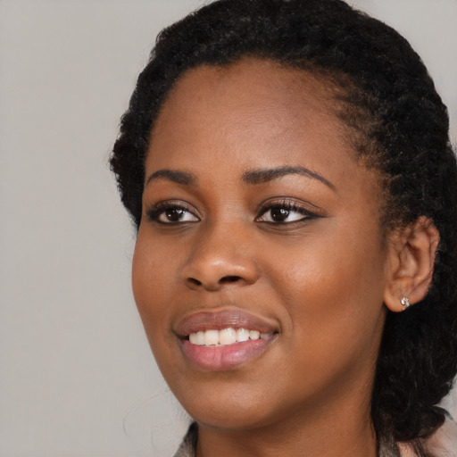 Joyful black young-adult female with long  black hair and brown eyes