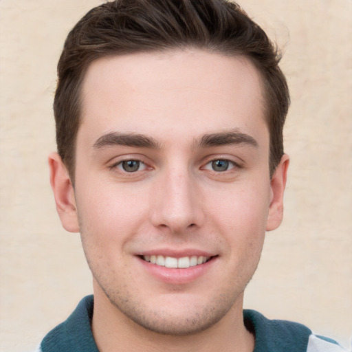 Joyful white young-adult male with short  brown hair and grey eyes