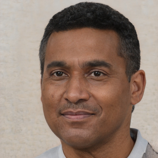 Joyful black adult male with short  black hair and brown eyes