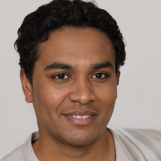 Joyful black young-adult male with short  black hair and brown eyes