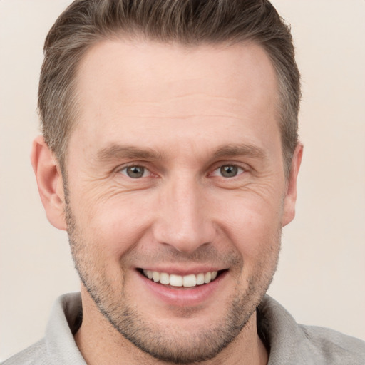 Joyful white adult male with short  brown hair and grey eyes