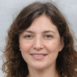 Joyful white adult female with long  brown hair and grey eyes