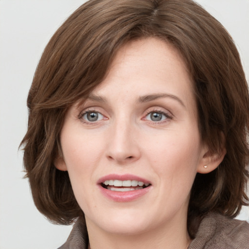 Joyful white young-adult female with medium  brown hair and grey eyes