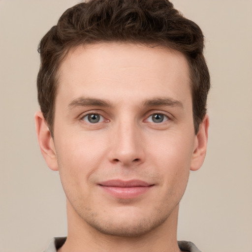 Joyful white young-adult male with short  brown hair and grey eyes