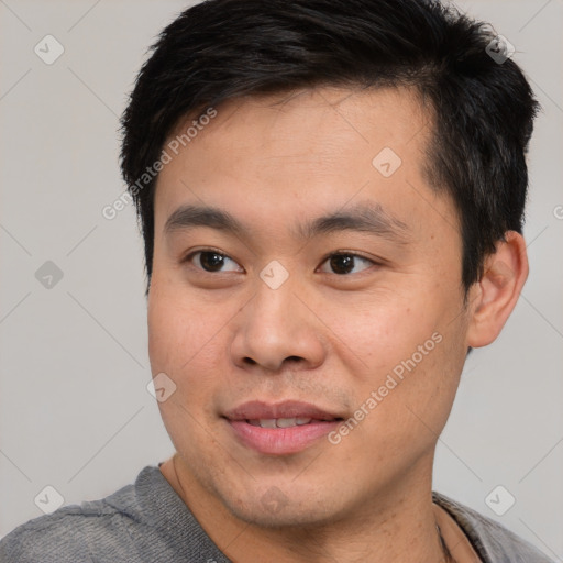 Joyful asian young-adult male with short  black hair and brown eyes