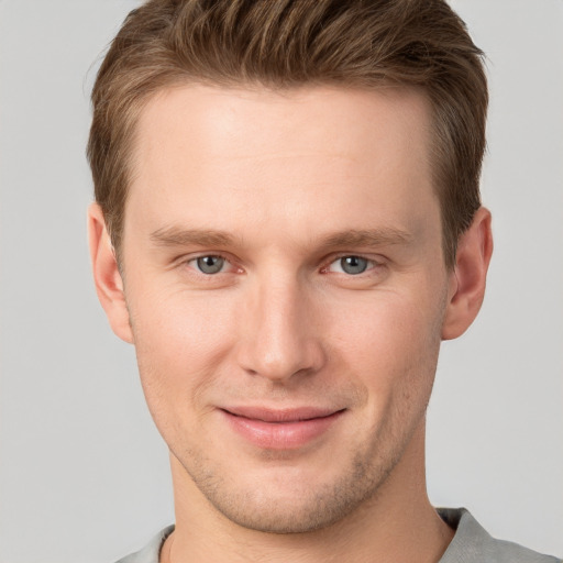 Joyful white young-adult male with short  brown hair and grey eyes