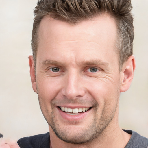 Joyful white adult male with short  brown hair and grey eyes