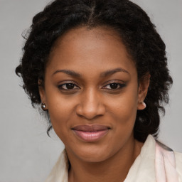 Joyful black young-adult female with long  brown hair and brown eyes