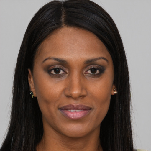 Joyful black young-adult female with long  brown hair and brown eyes