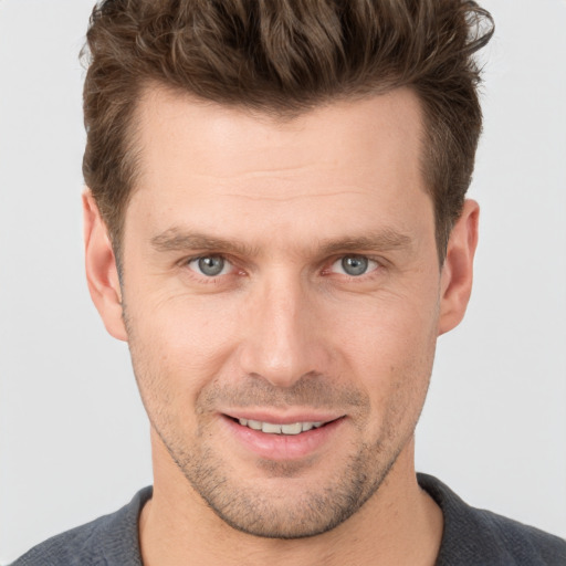 Joyful white young-adult male with short  brown hair and grey eyes