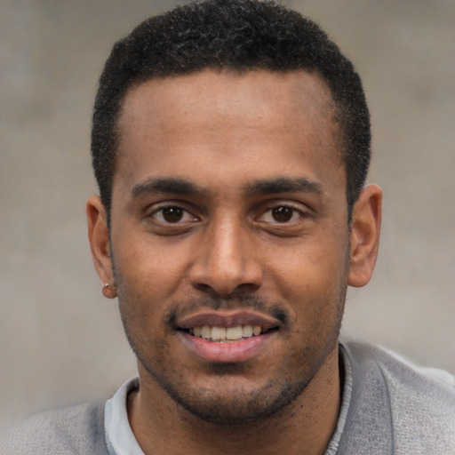 Joyful black young-adult male with short  black hair and brown eyes