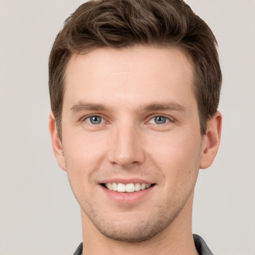 Joyful white young-adult male with short  brown hair and grey eyes