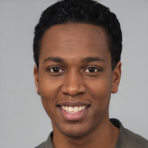 Joyful black young-adult male with short  black hair and brown eyes