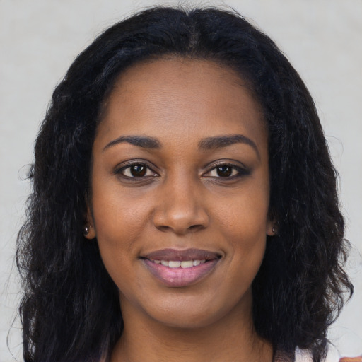 Joyful black young-adult female with long  black hair and brown eyes