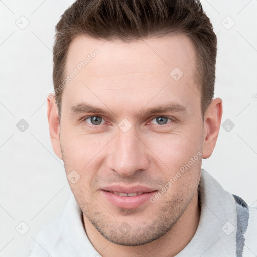 Joyful white young-adult male with short  brown hair and grey eyes