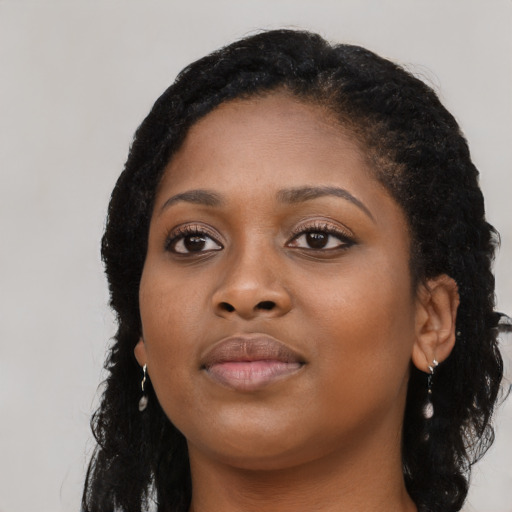 Joyful black young-adult female with long  black hair and brown eyes