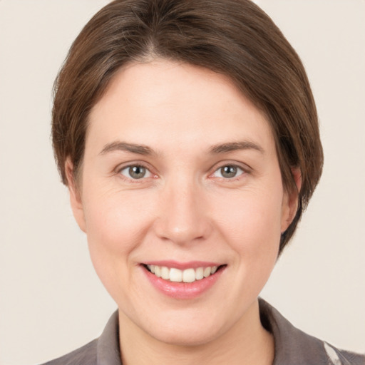 Joyful white young-adult female with short  brown hair and grey eyes