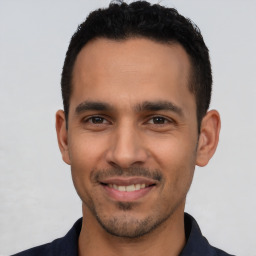 Joyful latino young-adult male with short  black hair and brown eyes