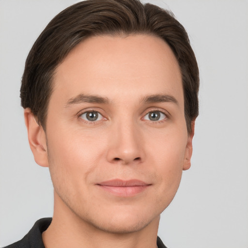 Joyful white young-adult male with short  brown hair and grey eyes