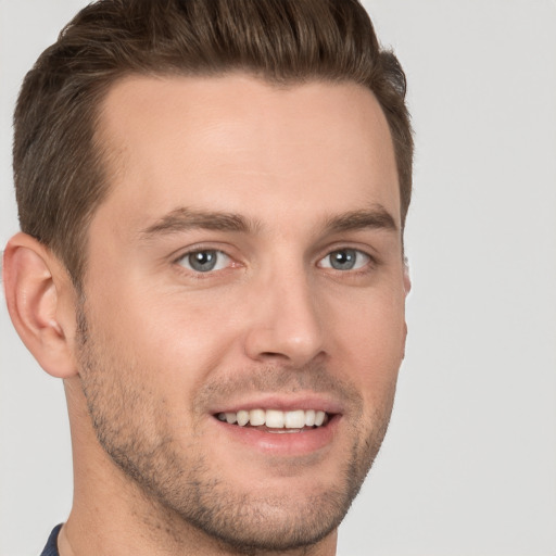 Joyful white young-adult male with short  brown hair and grey eyes