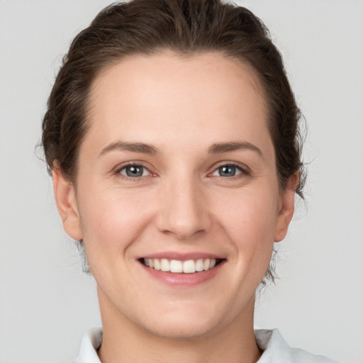 Joyful white young-adult female with short  brown hair and grey eyes