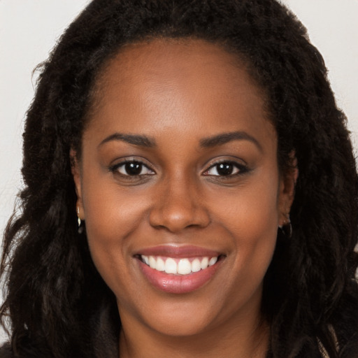 Joyful black young-adult female with long  brown hair and brown eyes