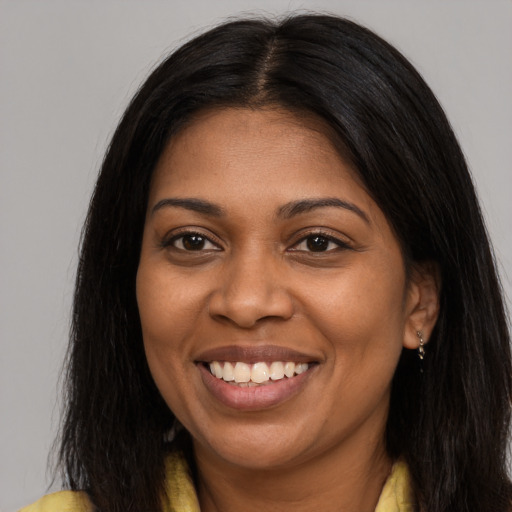 Joyful black young-adult female with long  brown hair and brown eyes