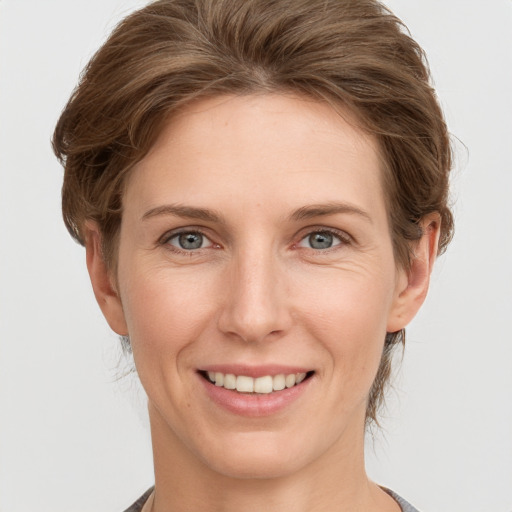 Joyful white young-adult female with medium  brown hair and grey eyes