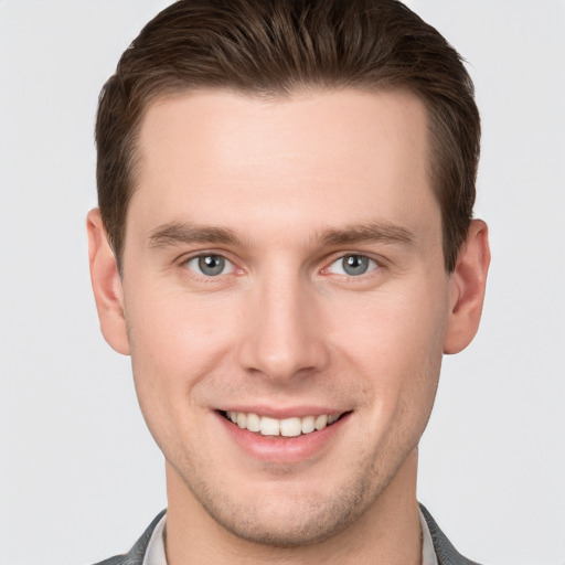 Joyful white young-adult male with short  brown hair and grey eyes