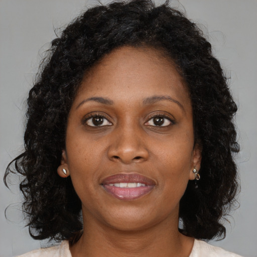 Joyful black young-adult female with long  brown hair and brown eyes