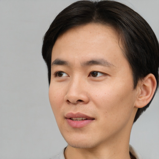Joyful asian young-adult male with short  brown hair and brown eyes