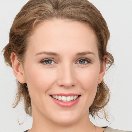 Joyful white young-adult female with medium  brown hair and grey eyes