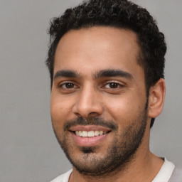 Joyful latino young-adult male with short  black hair and brown eyes