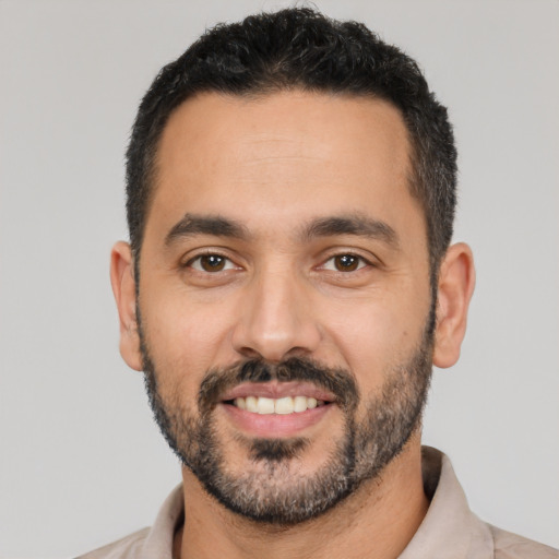 Joyful latino adult male with short  black hair and brown eyes