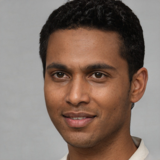 Joyful black young-adult male with short  brown hair and brown eyes