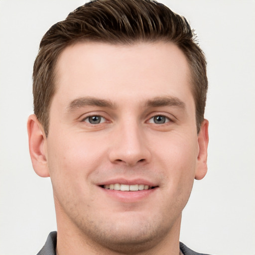 Joyful white young-adult male with short  brown hair and grey eyes