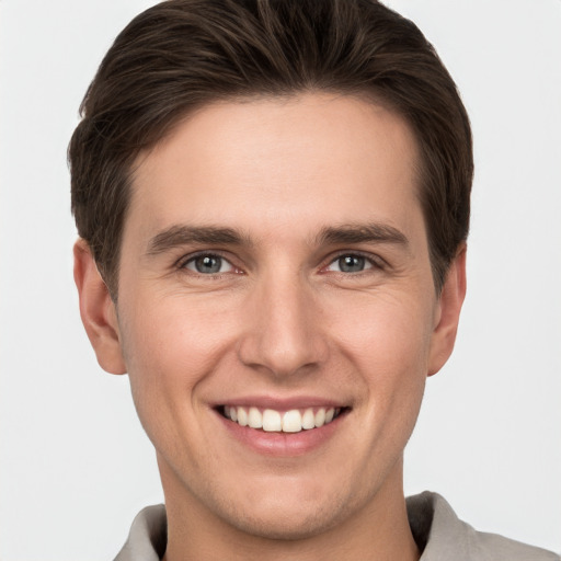 Joyful white young-adult male with short  brown hair and grey eyes