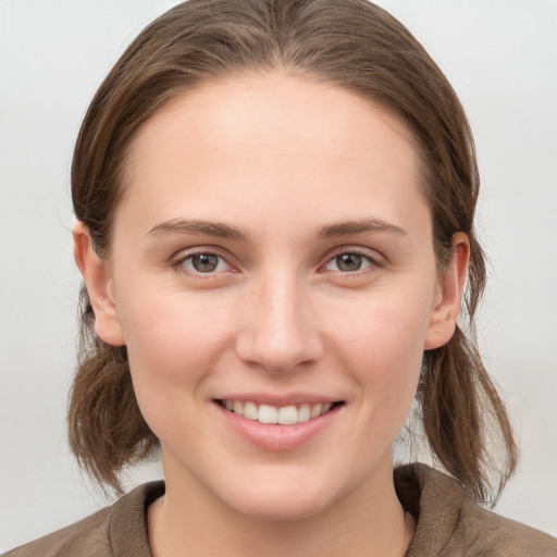 Joyful white young-adult female with medium  brown hair and grey eyes