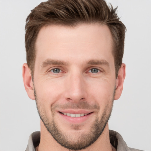 Joyful white young-adult male with short  brown hair and grey eyes