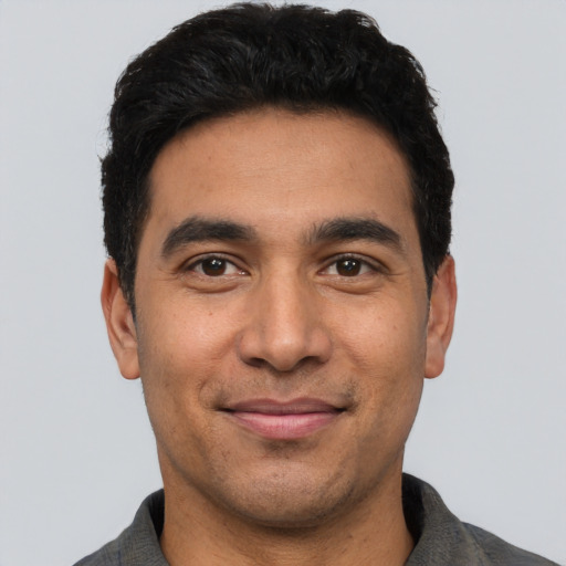 Joyful latino young-adult male with short  black hair and brown eyes