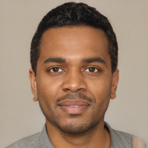 Joyful black young-adult male with short  black hair and brown eyes