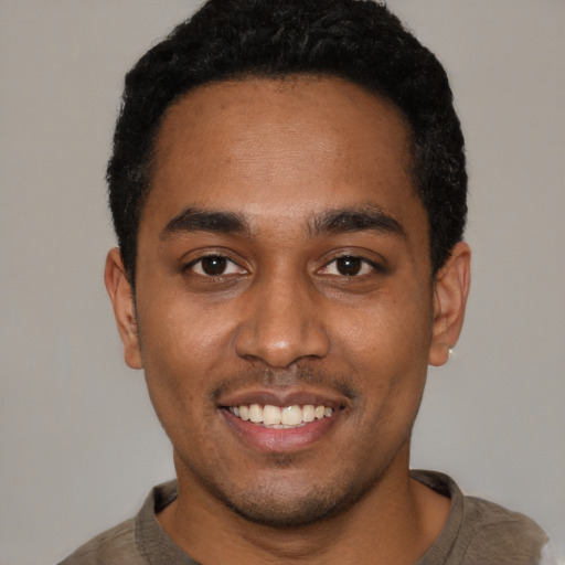 Joyful black young-adult male with short  black hair and brown eyes