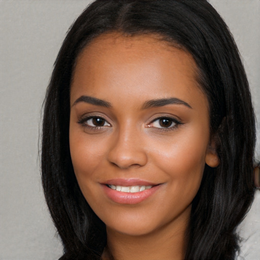 Joyful black young-adult female with long  brown hair and brown eyes