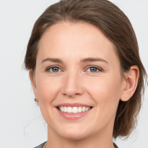 Joyful white young-adult female with medium  brown hair and grey eyes