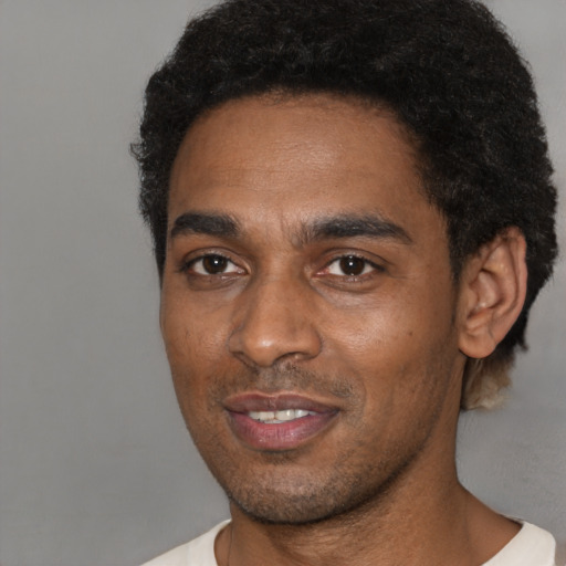 Joyful black young-adult male with short  black hair and brown eyes