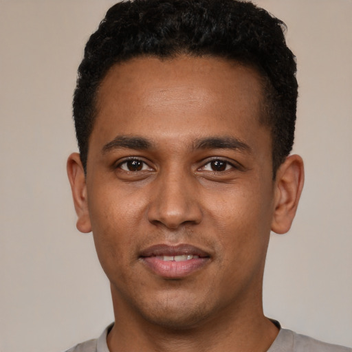 Joyful black young-adult male with short  black hair and brown eyes