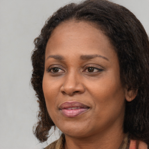 Joyful black adult female with long  brown hair and brown eyes