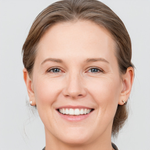 Joyful white young-adult female with medium  brown hair and grey eyes