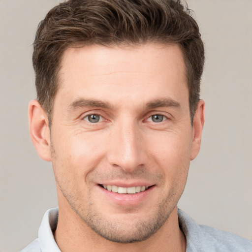 Joyful white young-adult male with short  brown hair and grey eyes