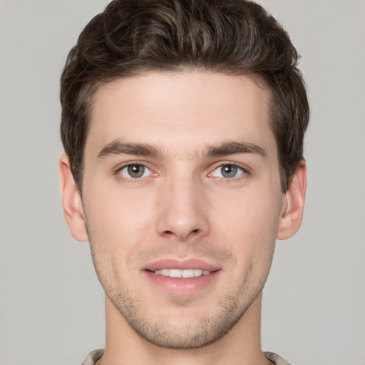 Joyful white young-adult male with short  brown hair and grey eyes